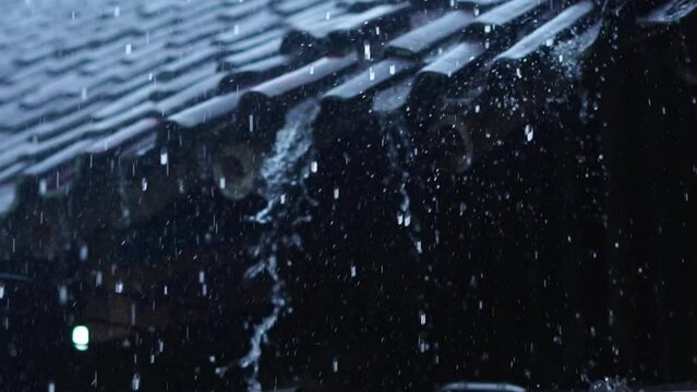 rainwater falling onto the roof of the house flows like a waterfall - slow motion b roll rainwater