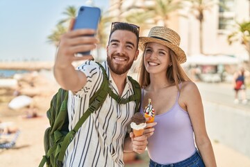 Man and woman tourist couple make selfie by smartphone eating ice cream at seaside