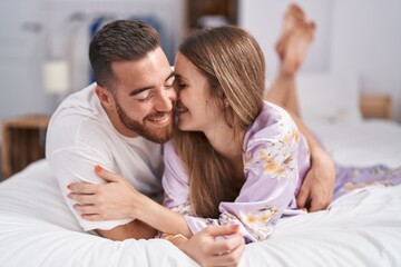 Man and woman couple lying on bed kissing at bedroom