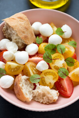 Close-up of salad with red and yellow tomatoes, mini mozzarella balls and beetroot leaves, vertical shot, selective focus