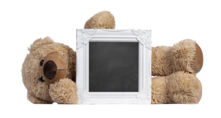 Cute new light brown toy teddy bear laying behind white empty photo frame. Isolated Cute new light brown toy teddy bear laying behind white empty photo frame. Isolated cutout on transparent background