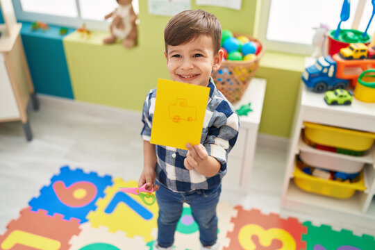 Adorable hispanic boy preschool student showing draw at kindergarten