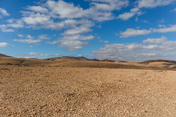 amazing desert landscape with blue sky and white clouds with mountain range in the background....