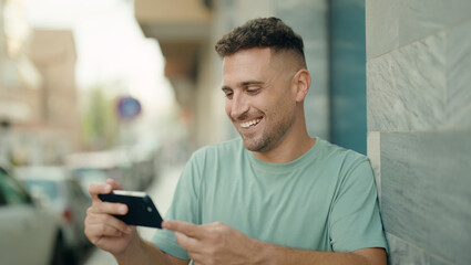 Young hispanic man smiling confident watching video on smartphone at street