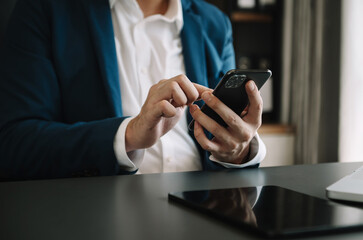 Businessman hand using smart phone laptop and tablet with social network diagram on desk as concept.