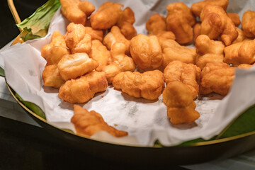 Deep-fried traditional Thai dough, deep-fried dough ready to serve for snack breakfast, warm light from above.