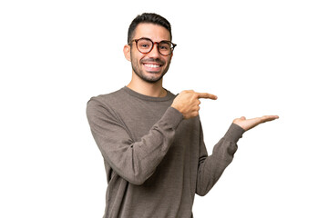 Young handsome caucasian man over isolated background holding copyspace imaginary on the palm to...