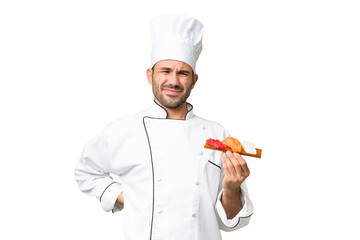 Young caucasian chef holding a sushi over isolated background suffering from backache for having...