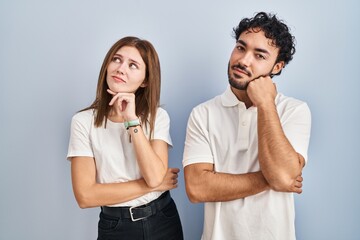 Young couple wearing casual clothes standing together with hand on chin thinking about question, pensive expression. smiling with thoughtful face. doubt concept.