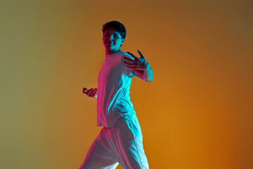 man dancing on yellow background. Neon lighting