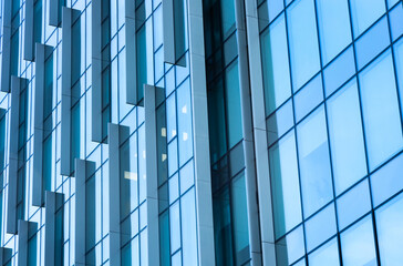 The blue sky is reflected in the windows of a modern office building. Architecture and exterior of contemporary houses