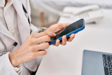 Young caucasian woman doctor using smartphone working at clinic