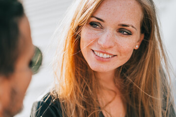 Close up redhead American woman toothy smiles looks at boyfriend tenderly, Couple in love dating. Happy caucasian girl looking at husband, feels love. Newlyweds at travel. Romance, relationship.