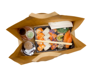 Sushi to go concept. Top view of takeaway box with sushi rolls and various sauce cups in brown paper bag.