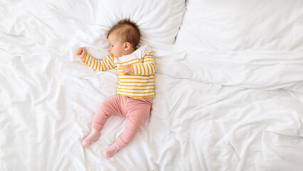 High-angle view of adorable baby girl napping on white blanket on bed during daytime, top view, panorama with copy space