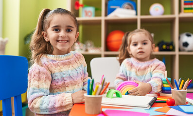 Two kids preschool students sitting on table drawing on paper at kindergarten