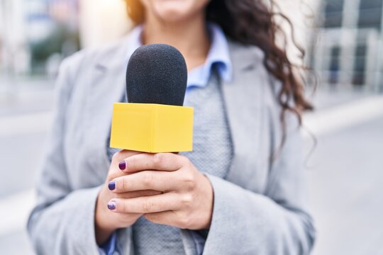 Young Hispanic Woman Reporter Working Using Microphone At Street