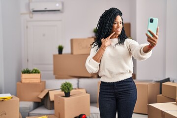 Fototapeta na wymiar Middle age hispanic woman moving to a new home taking selfie picture smiling happy pointing with hand and finger