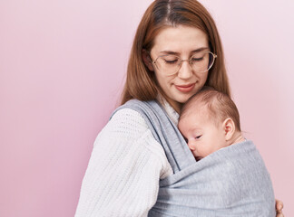 Mother and son hugging each other standing over isolated pink background