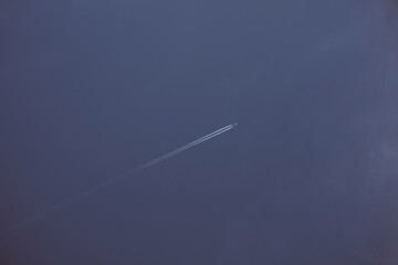 Aereo da trasporto passeggeri in alta quota con scie bianche provenienti dai motori. Sfondo di cielo blu.