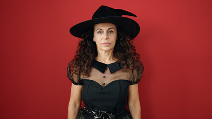 Middle age hispanic woman wearing witch costume having halloween party over isolated red background