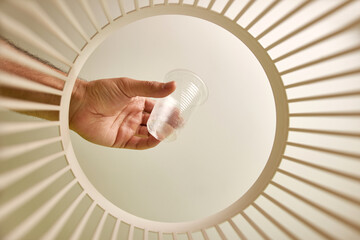 A plastic cup is thrown into the trash for disposal and recycling. View from below. The concept of...