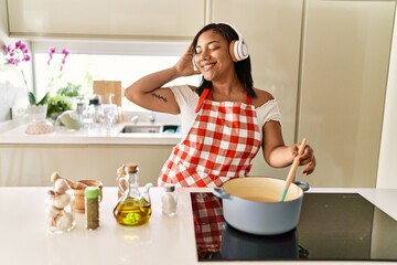 Hispanic brunette woman cooking wearing headphones at the kitchen