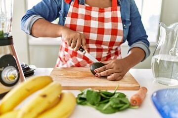 Hispanic brunette woman preparing fruit smoothie at the kitchen