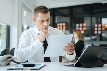 Business man using digital tablet analyzes business data, busy working on laptop computer with smart phone and business report on office desk, business strategy analysis concept.