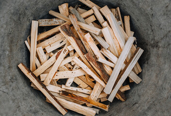 Chopped, sawn boards, firewood lie in a metal tank, bowl. Close-up photo, texture, top view.