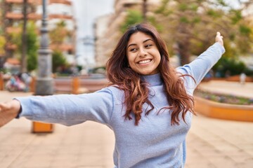 Young hispanic woman smiling confident standing with open arms at park