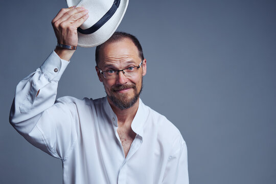 Smiling middle age man in straw hat lifting his hat welcoming