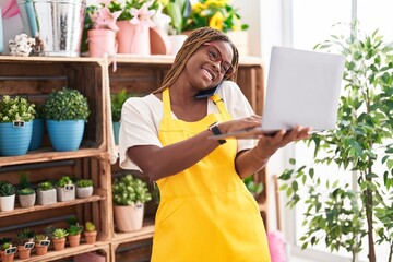 African american woman florist talking on smartphone using laptop at florist