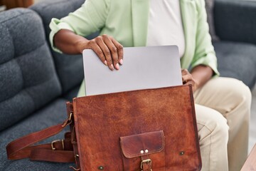 African american woman psychologist holding laptop of briefcase at psychology center