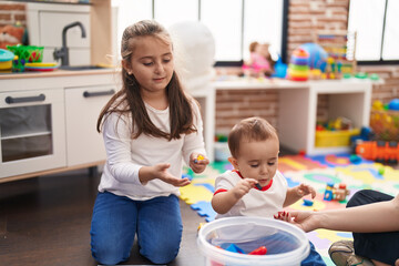 Brother and sister playing with construction blocks sitting on floor at kindergarten