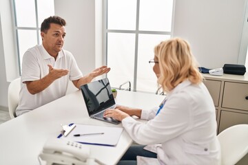 Fototapeta premium Middle age man and woman doctor and patient having medical consultation at clinic