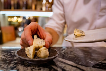 man chef hand takes cheese cubes on plate