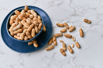 Image of bunch of peanuts in a bowl on a marble table