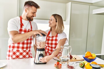 Young couple smiling confident making smoothie using blender at kitchen