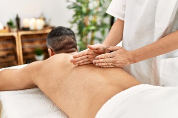 Obraz na płótnie Canvas Young hispanic man having back massage at beauty center