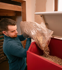 Man loads wood pellets in the solid fuel boiler. Concept of heating stove working with biofuels and...