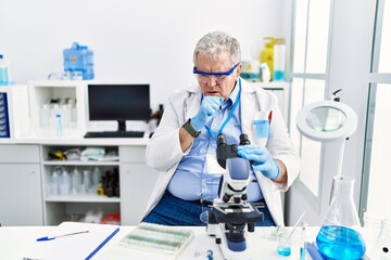 Senior caucasian man working at scientist laboratory feeling unwell and coughing as symptom for cold or bronchitis. health care concept.