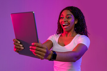 Naklejka premium Online Gaming Concept. Surprised black woman looking at digital tablet screen