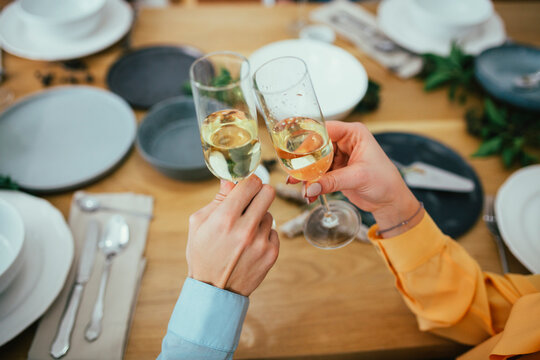 Cropped image of friends toasting champagne flutes while sitting at dining table