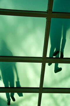 Shadows of people crossing translucent walkway at Lisbon shopping mall, Portugal.