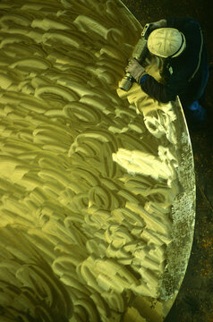 Overhead view of worker polishing propeller at shipyard in Busan, South Korea.