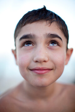 A young boy smiles slightly and looks up.