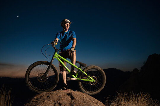 A man performs trial bike standing on a rock at El Diente, Jalisco, Mexico.