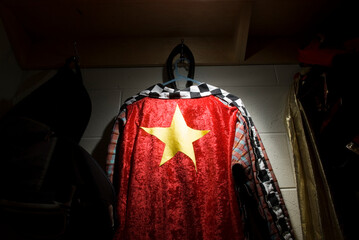 A circus performer costume featuring a gold star against a red background hung in the locker room.