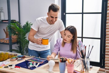 Man and woman artists couple drawing on notebook drinking coffee at art studio
